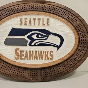 Oval wooden cribbage board with Seattle Seahawks logo in navy blue and gray on white textured center